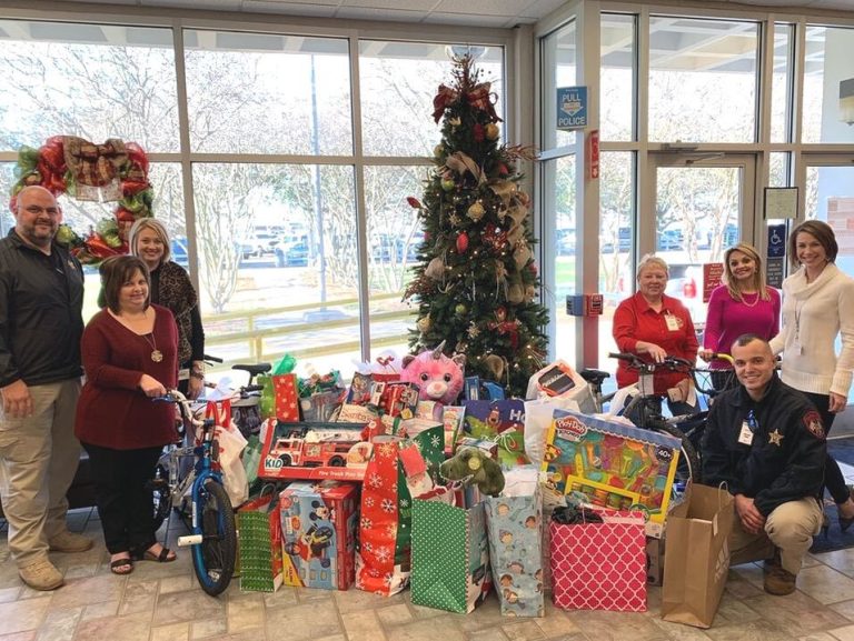 Sponsoring Kids This Holiday Season, Rubicon Employees standing around Christmas tree in lobby with a large amount of presents and children's toys beneath it